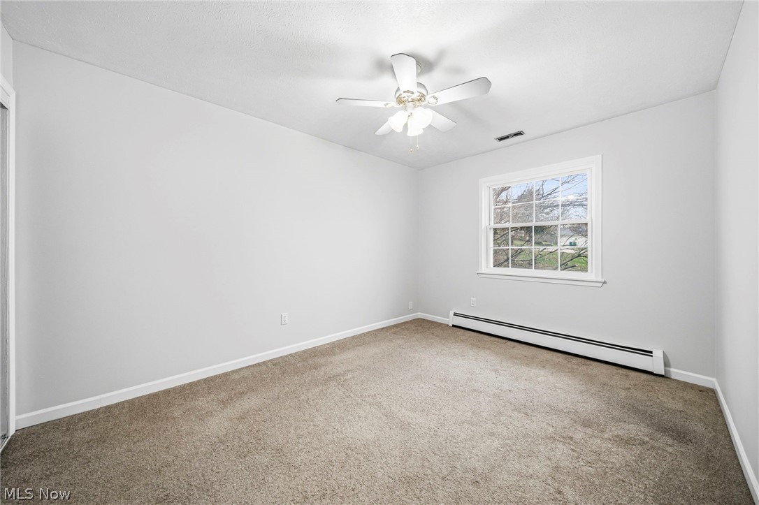 10397 Prouty Road Painesville, OH 44077 - Photo 13 of 32 Empty room featuring a baseboard radiator, a ceiling fan, and light carpet