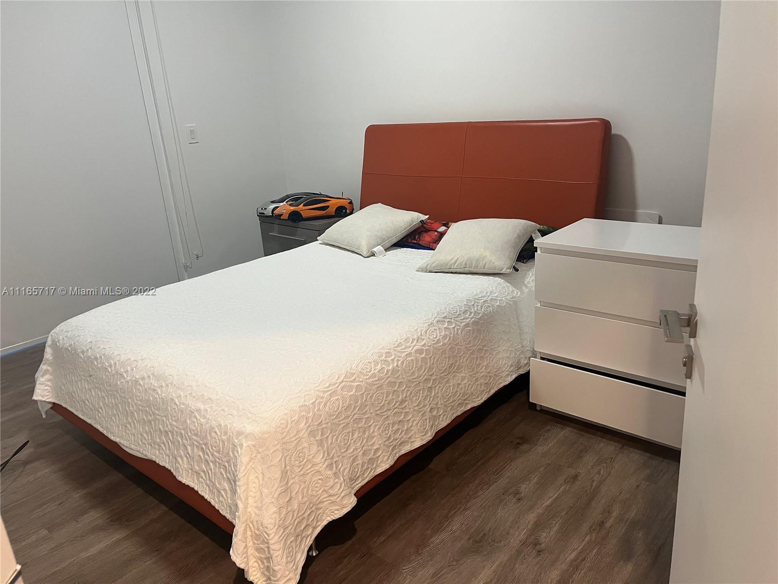 Doral Isles Doral, FL 33178 - Photo 22 of 37 a bed sitting in a bedroom next to a window with wooden floor