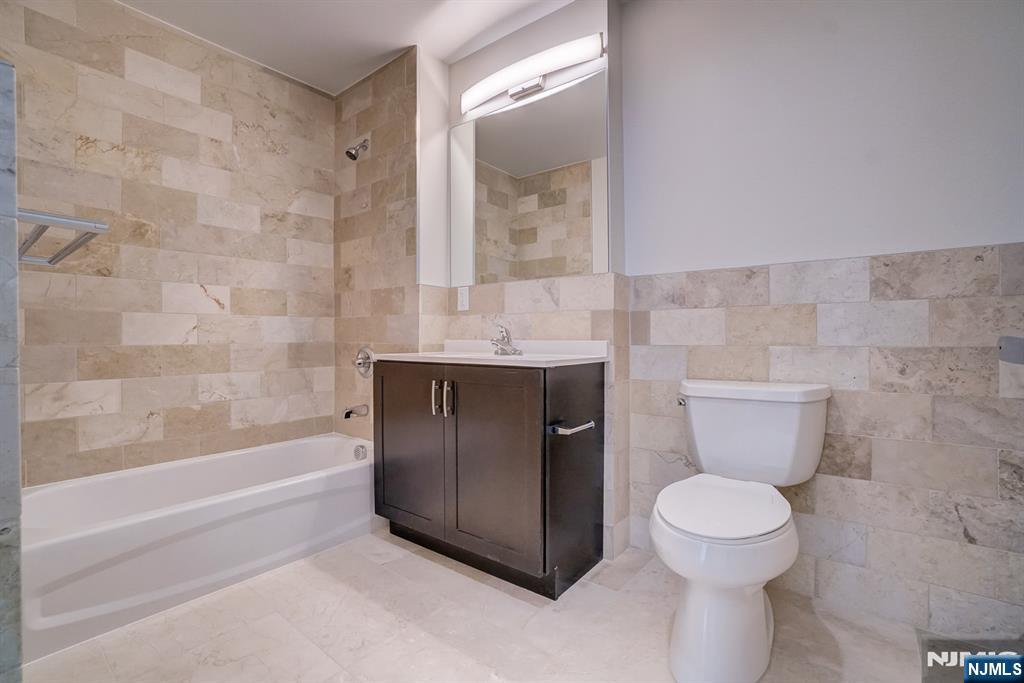 69 Main Street, Unit 1115 Fort Lee, NJ 07024 - Photo 6 of 13 a bathroom with a granite countertop toilet a sink and bathtub