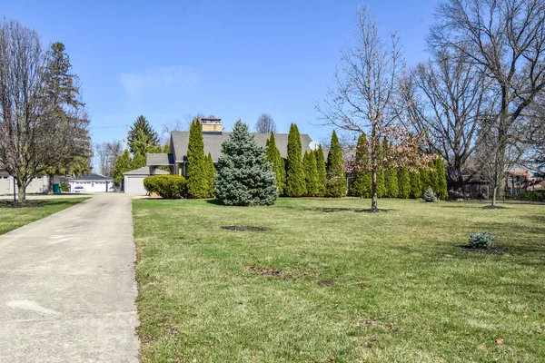 a view of a white house with a small yard and large tree