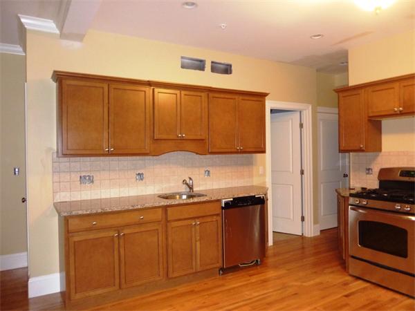 81 Ash Street, Unit 2 Waltham, MA 02453 - Photo 3 of 5 a kitchen with stainless steel appliances granite countertop a sink stove and cabinets