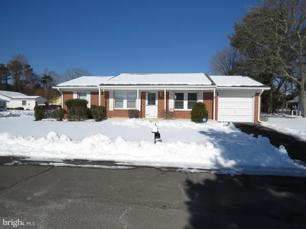 a front view of a house with a yard covered with snow