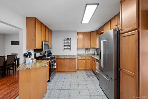 a large kitchen with a refrigerator a sink dishwasher a stove a dining table and chairs with wooden floor