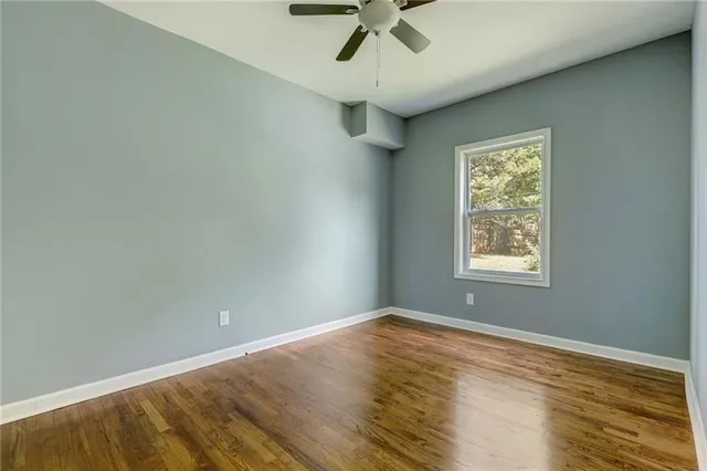 an empty room with a window and ceiling fan
