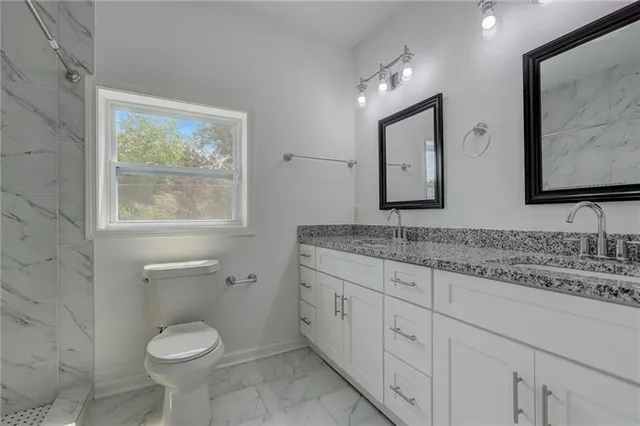 a bathroom with a granite countertop toilet sink and mirror