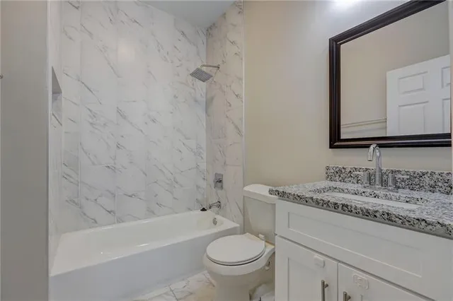 a bathroom with a granite countertop toilet a sink and a bathtub