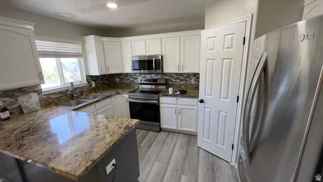 3547 East Golden Eagle Road Eagle Mountain, UT 84005 - Photo 6 of 47 Kitchen featuring stainless steel appliances, white cabinets, light stone countertops, light wood-style flooring, and recessed lighting