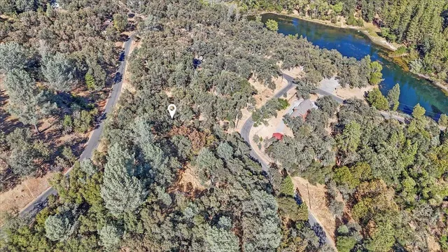 a view of a wooden house with a yard and large tree