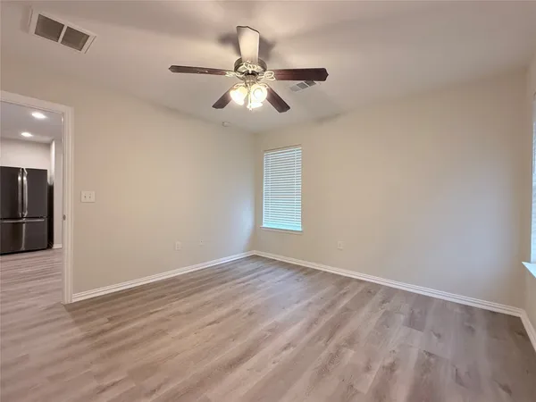 a view of an empty room with wooden floor and a ceiling fan