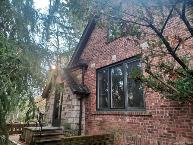a view of a brick house with large windows and a large tree