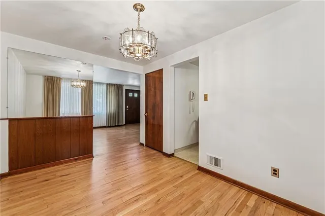 a view of a hallway with wooden floor and a chandelier