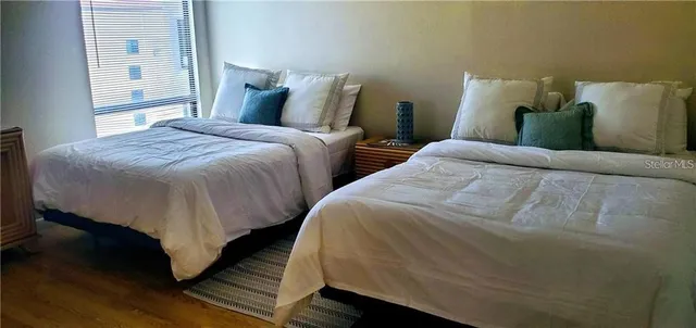 a large bed sitting in a bedroom next to a window and a wooden floor