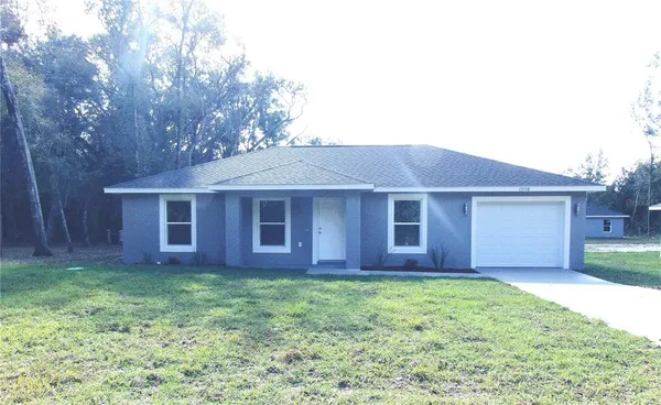 a brick house next to a yard with large trees