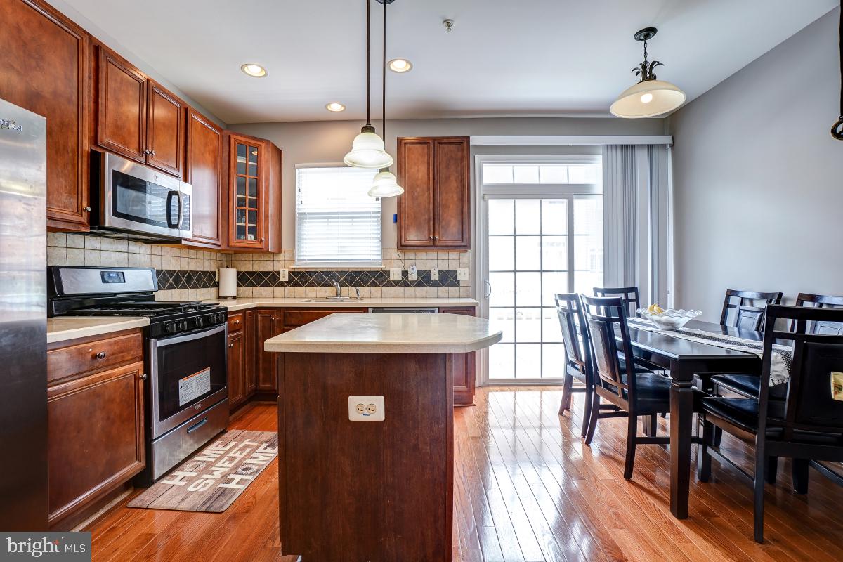 4281 South Capitol Street Southwest Washington, DC 20032 - Photo 34 of 71 a kitchen with stainless steel appliances granite countertop a stove top oven a sink dishwasher a dining table and chairs with wooden floor