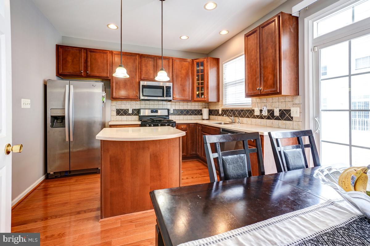 4281 South Capitol Street Southwest Washington, DC 20032 - Photo 42 of 71 a kitchen with stainless steel appliances granite countertop a stove a refrigerator a kitchen island a sink dishwasher a dining table and chairs with wooden floor