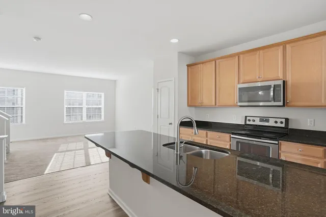 a kitchen with stainless steel appliances granite countertop a sink a stove a microwave a counter top space and cabinets