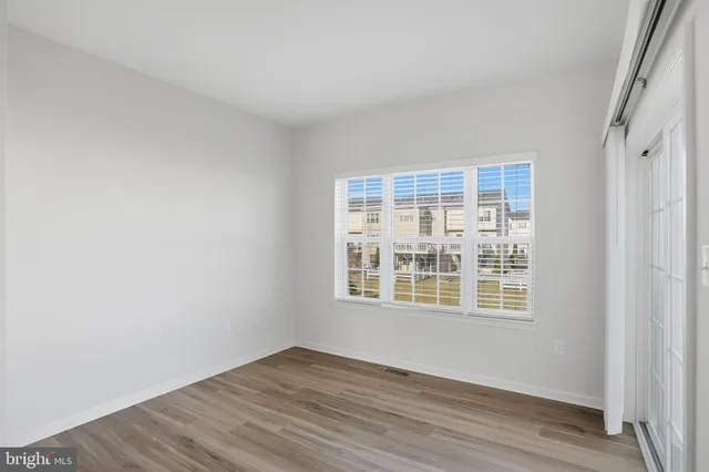 a view of an empty room with wooden floor and windows