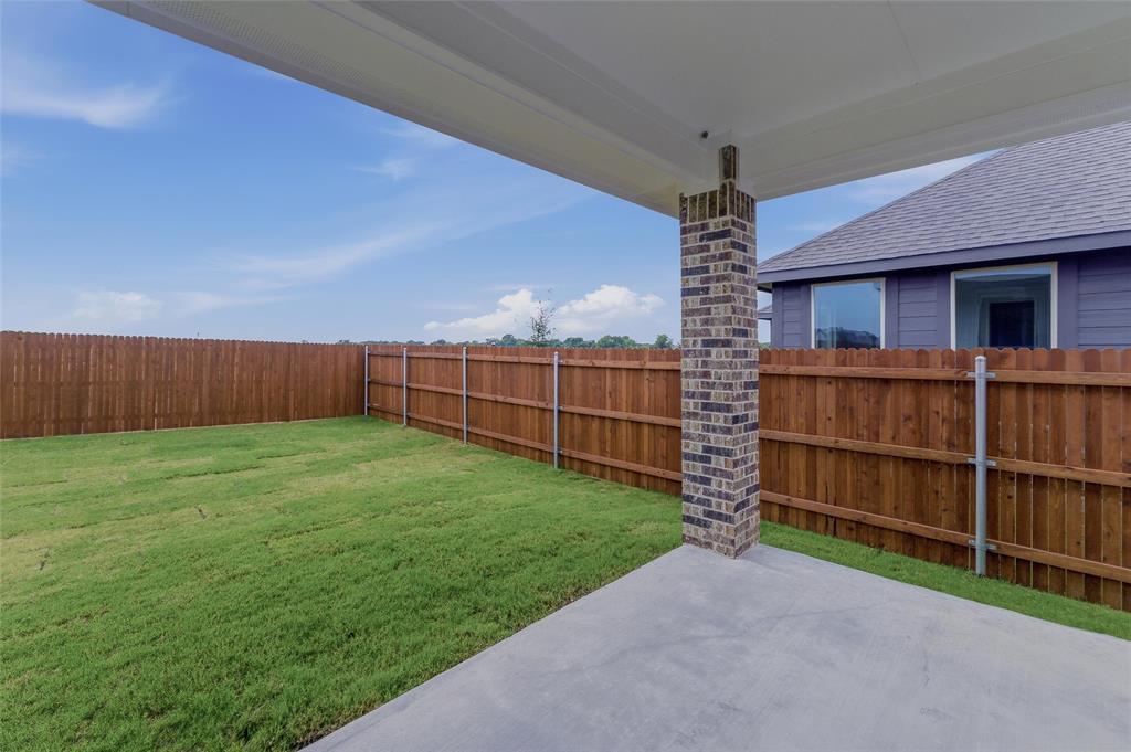 1329 Frio Drive Springtown, TX 76082 - Photo 20 of 25 Expansive backyard featuring a concrete patio, brick support column, wood privacy fencing, and green lawn space