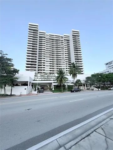 a front view of a building with road and trees