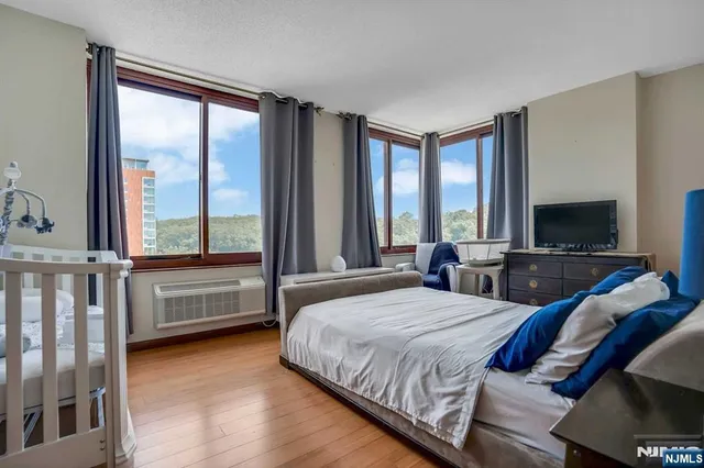 a bedroom with a bed and a flat tv screen next to a window
