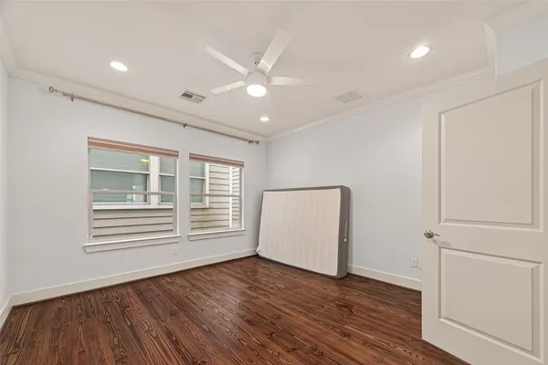 a view of empty room with wooden floor and fan