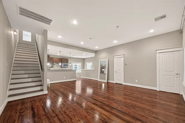 a view of an empty room with wooden floor and stairs
