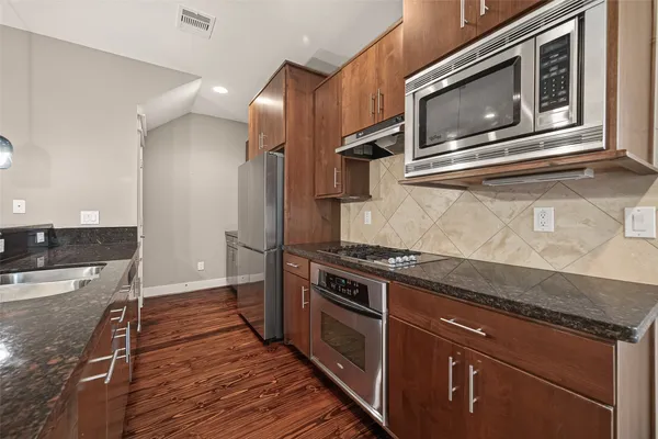 a kitchen with stainless steel appliances granite countertop a stove microwave and sink