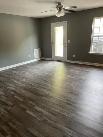 an empty room with wooden floor chandelier and windows