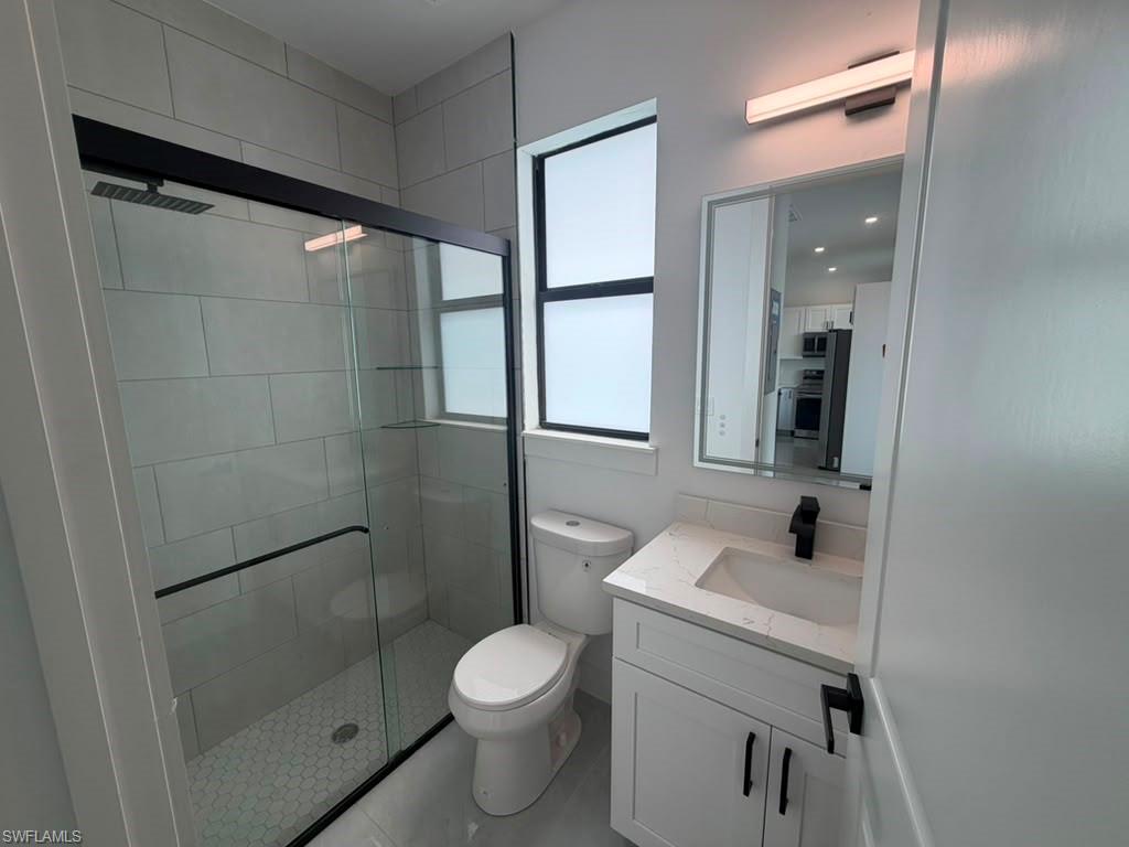 907 Homestead Road South Lehigh Acres, FL 33974 - Photo 35 of 43 Modern bathroom featuring a glass-enclosed shower with black trim, a wall-mounted showerhead, and hexagonal floor tiling