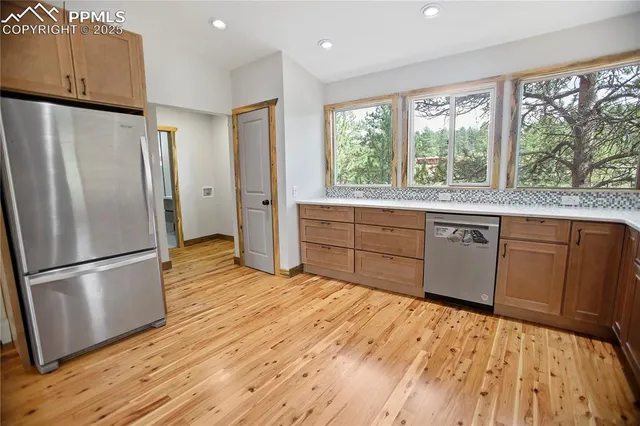 a kitchen with stainless steel appliances granite countertop a refrigerator a sink and wooden floors