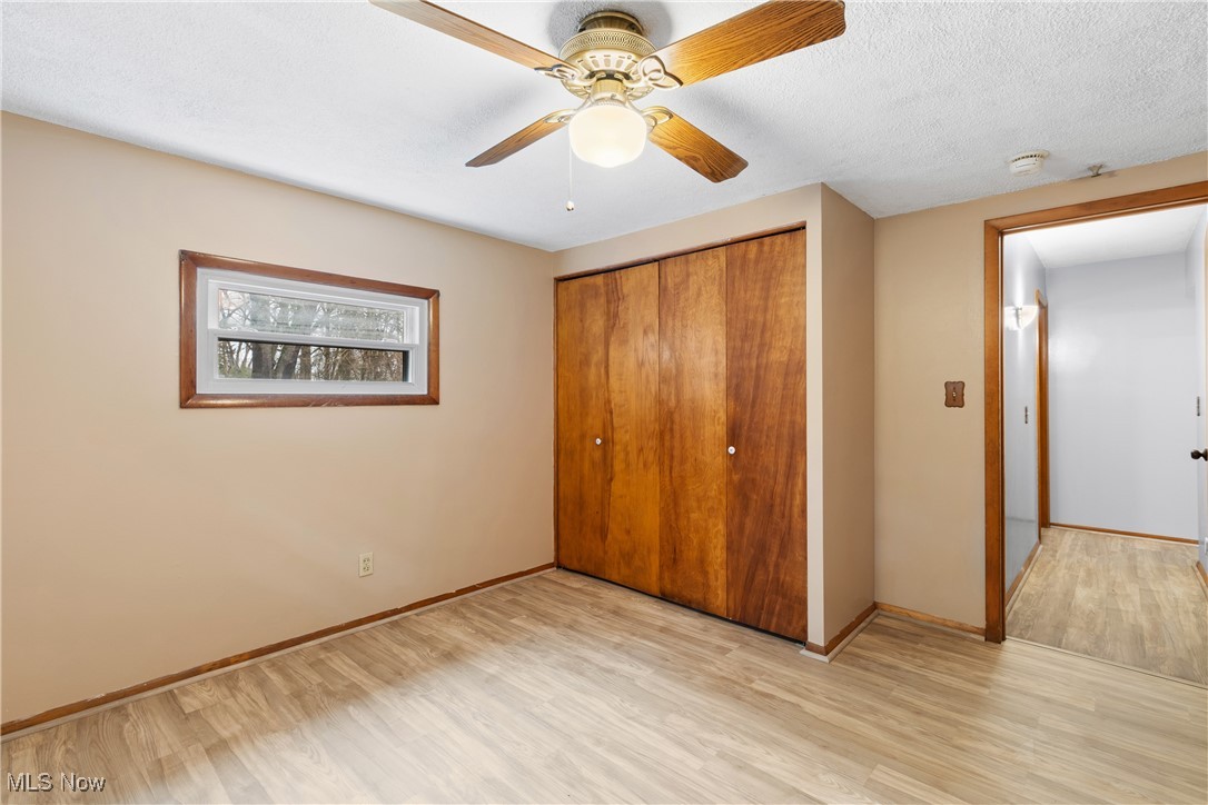 5415 12th Street Northwest Canton, OH 44708 - Photo 18 of 35 Unfurnished bedroom with light wood-style flooring, a textured ceiling, a closet, baseboards, and ceiling fan