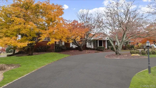 a front view of a house with garden and trees