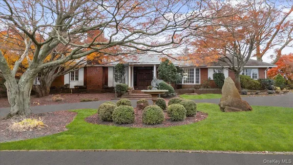a front view of a house with garden and trees