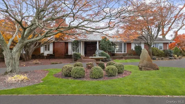 a front view of a house with garden and trees
