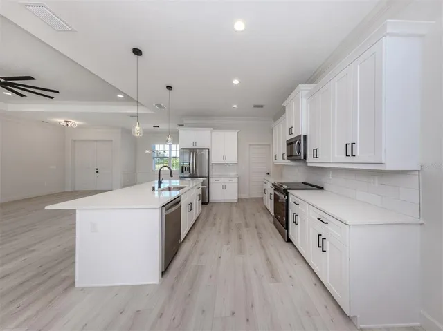 a large kitchen with stainless steel appliances sink a microwave and cabinets