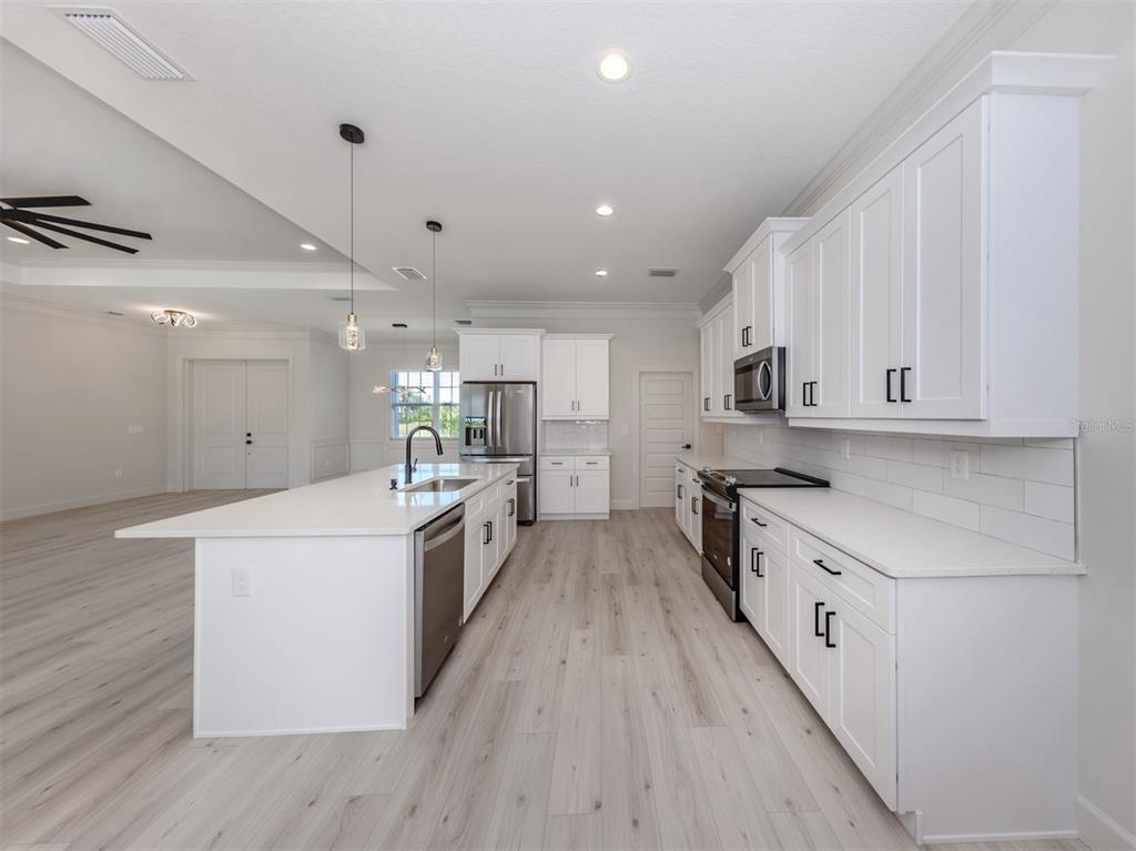 65 Fairway Road Rotonda West, FL 33947 - Photo 16 of 40 a large kitchen with stainless steel appliances sink a microwave and cabinets