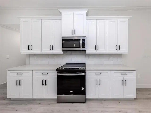 a kitchen with white cabinets and black appliances
