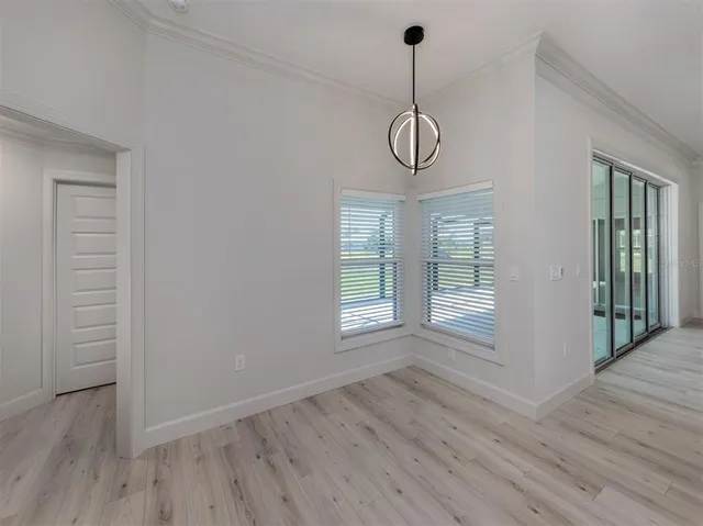 a view of an empty room with wooden floor and windows