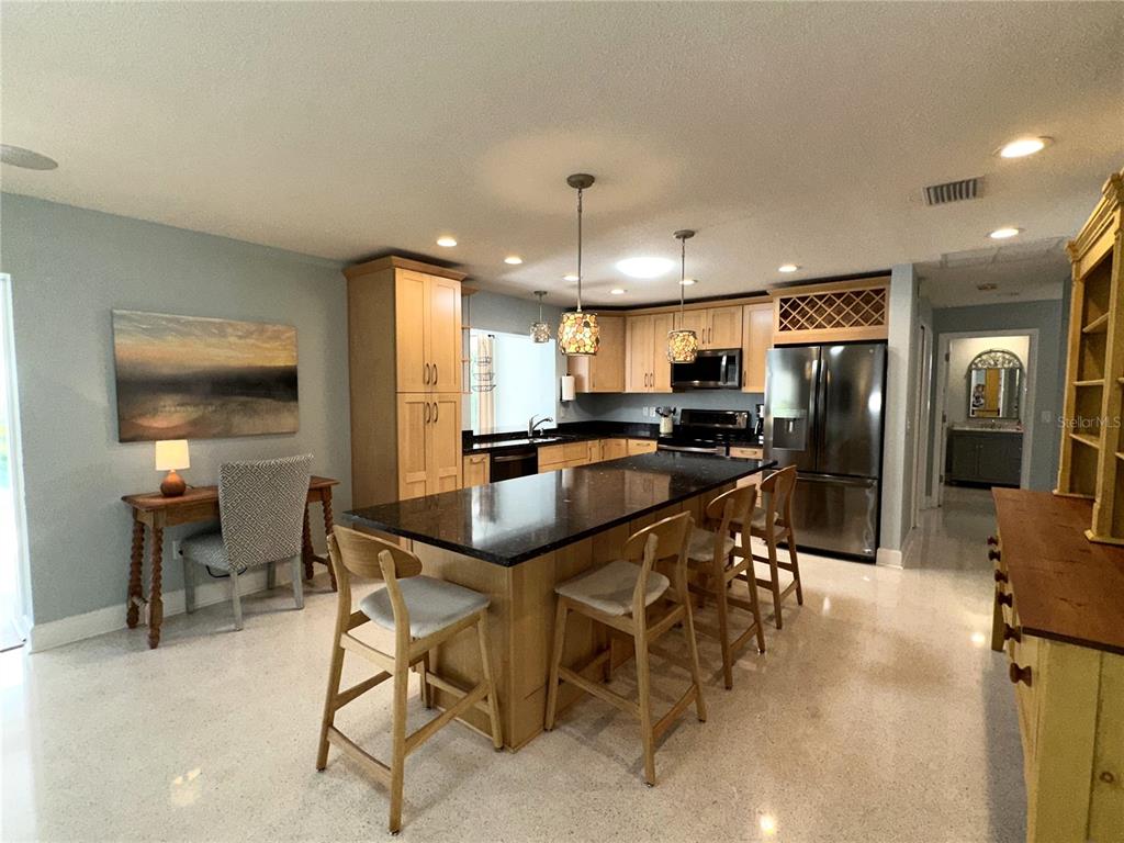 1883 Riviera Circle Sarasota, FL 34232 - Photo 11 of 45 a kitchen with stainless steel appliances kitchen island granite countertop a refrigerator a stove a sink a dining table and chairs with wooden floor