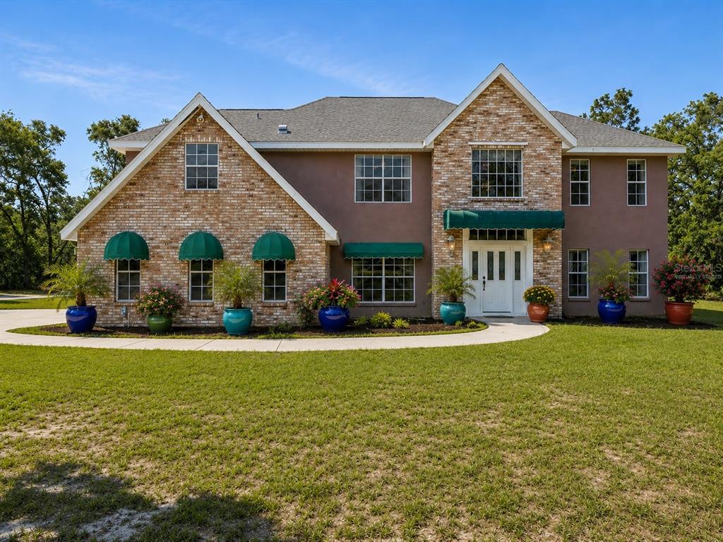 15420 Aubrey Avenue Spring Hill, FL 34610 - Photo 3 of 28 a front view of a house with a yard and garage