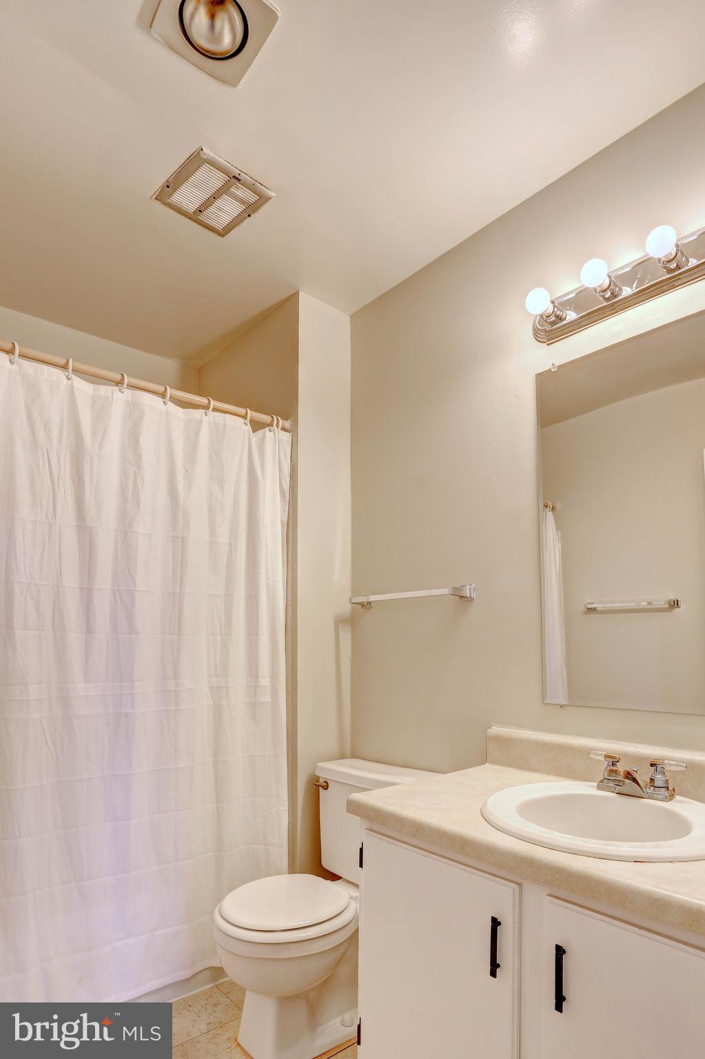 9110 Tumbleweed Run, Unit G Laurel, MD 20723 - Photo 18 of 32 a bathroom with a sink a toilet a mirror and shower curtain