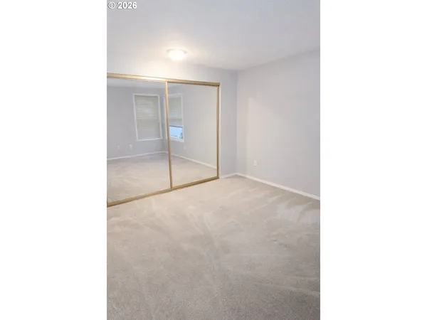 a view of an empty room with kitchen and a window