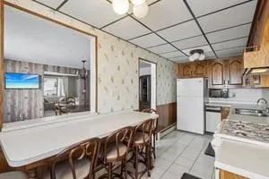 a kitchen with stainless steel appliances granite countertop a sink a stove a refrigerator a table and chairs