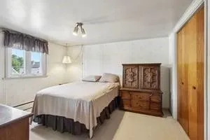 a bedroom with a bed a dresser and next to a window