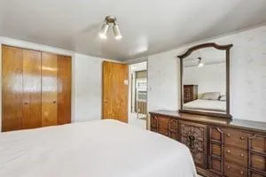 a bedroom with a bed and a large mirror on the dresser