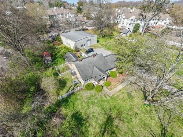 an aerial view of residential house with outdoor space and trees all around