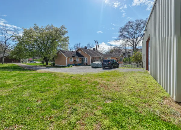 a view of a house with a big yard and large trees