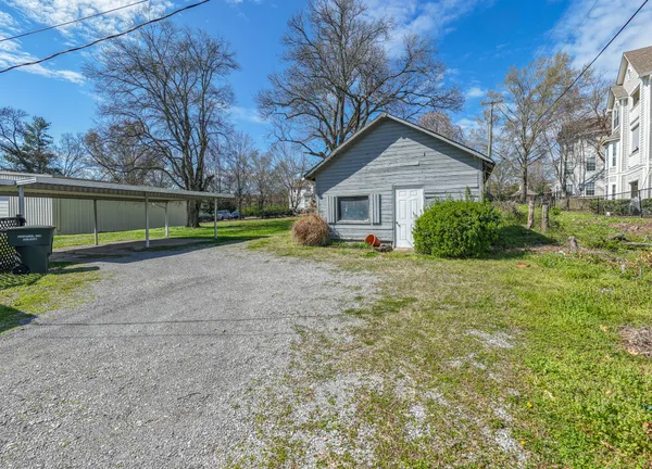 a view of a house with a yard and large trees