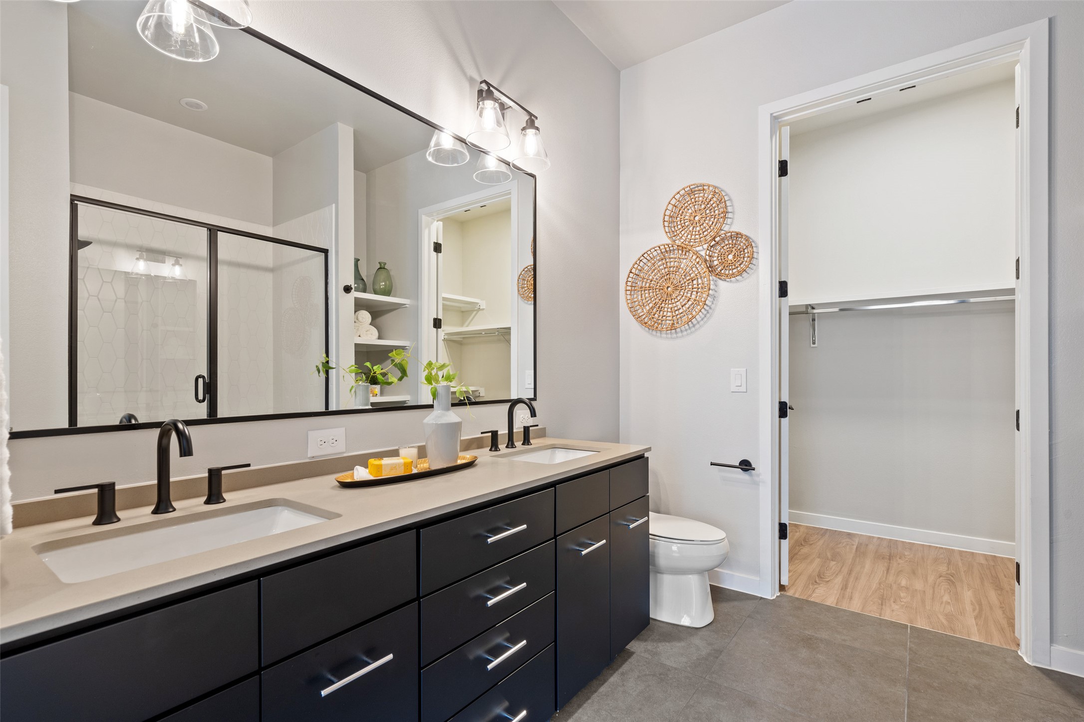 4510 Terry-O Lane, Unit 341 Austin, TX 78745 - Photo 29 of 40 Bathroom featuring a double vanity with dark cabinetry and light countertops, a rectangular mirror, and a shower with a glass enclosure