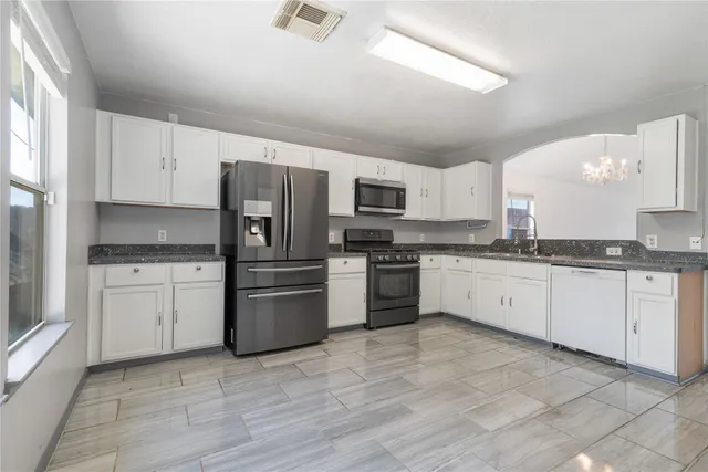 a kitchen with granite countertop a refrigerator sink and stove